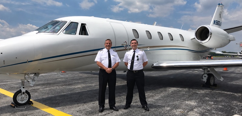 Pilots in uniform standing in front of Citation Excel N560AD